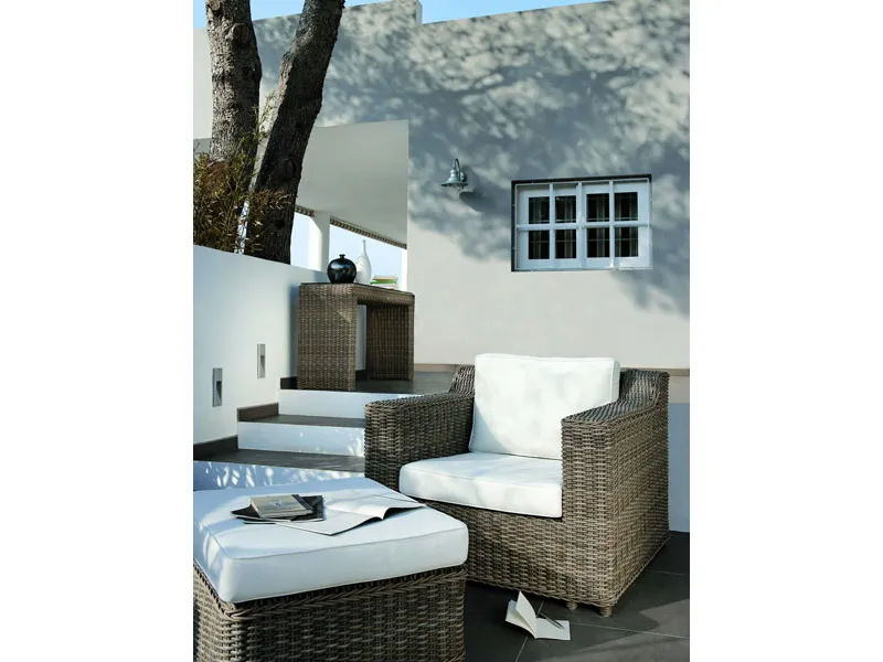 terrazza outdoor con mobili in bambù e cuscini bianchi, quaderni su pouf e tre gradini