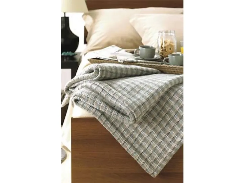dettaglio di coperta ripiegato su bordo letto con vassoio in materiale organico per colazione