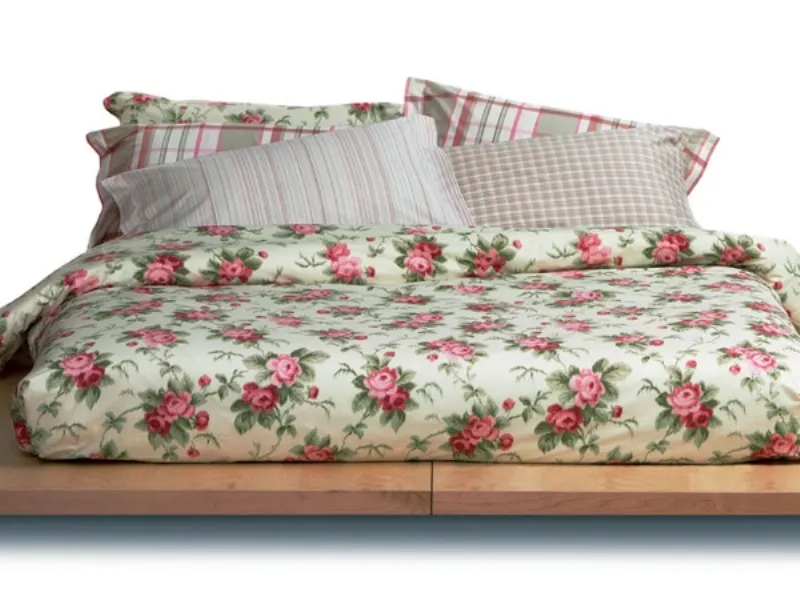 letto matrimoniale con copripiumino panna con rose e cusicni a righe abbinati