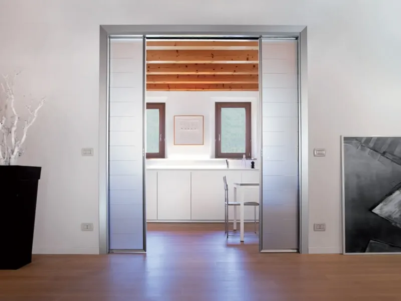 Controtelaio con illuminazione, interruttori e prese sulla parete. Soluzione per due ante speculari a scomparsa.