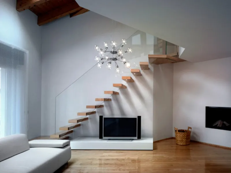 zona living con divano bianco, caminetto e scala con gradini in legno chiaro, lampada da parete con bracci e bulbi trasparenti