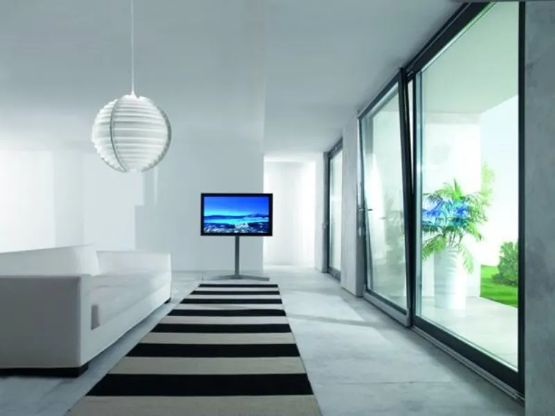 zona living con divano banco, tappeto a righe bianche e nere, lampada sferica in carta, parete finestrata