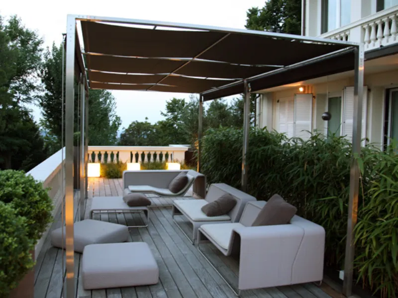 veduta su terrazzo con parquet e gazebo, divani, pouf e tavolino design bianchi con cuscini marroni