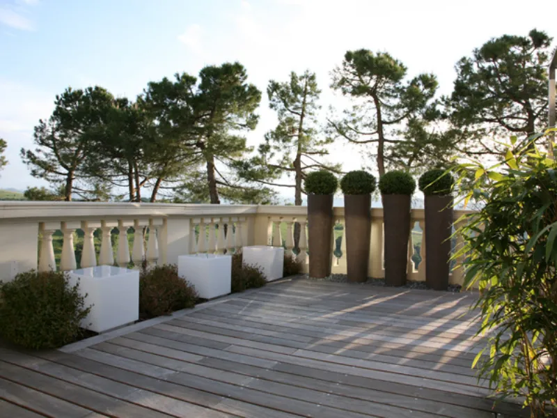 veduta di angolo di terrazzo con parquet e vasi con siepi sferiche e cubi luminosi bianchi
