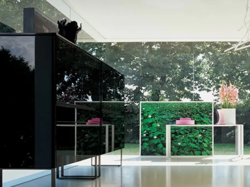 mobile da zona living in nero lucido, tavolino bianco con vaso bianco e fiori rosa, quadro con ninfee e parete vetrata