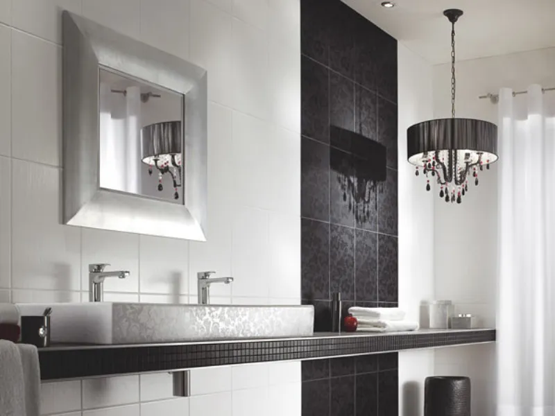 arredo bagno con piastrelle bianche e nere, lampadario con paralume circolare nero e gocce, specchio quadrato con cornice argentata
