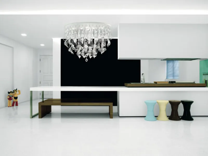 lampadario in cristalli e vetri trasparenti, penisola cucina bianca con quattro sgabelli colorati e panca in legno