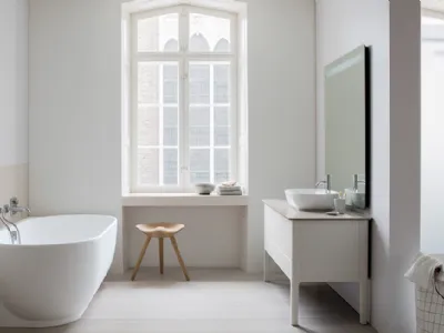 Serie Luv di Duravit. Bagno con vasca appoggiata al muro e console in legno con lavamani