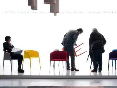 spazio espositivo con sedute multicolore e tre visitatori