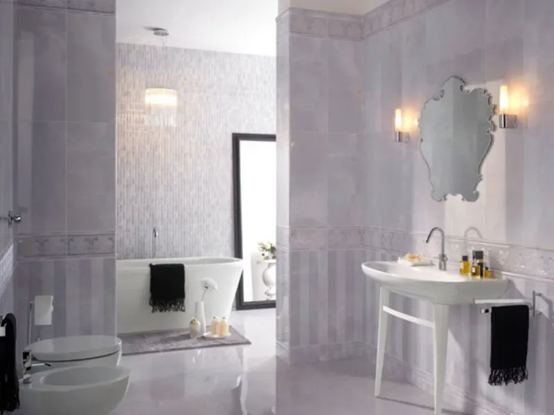bagno nei toni del lilla con sanitari in porcellana bianca, specchio rettangolare appoggiato a parete, e specchio rococò