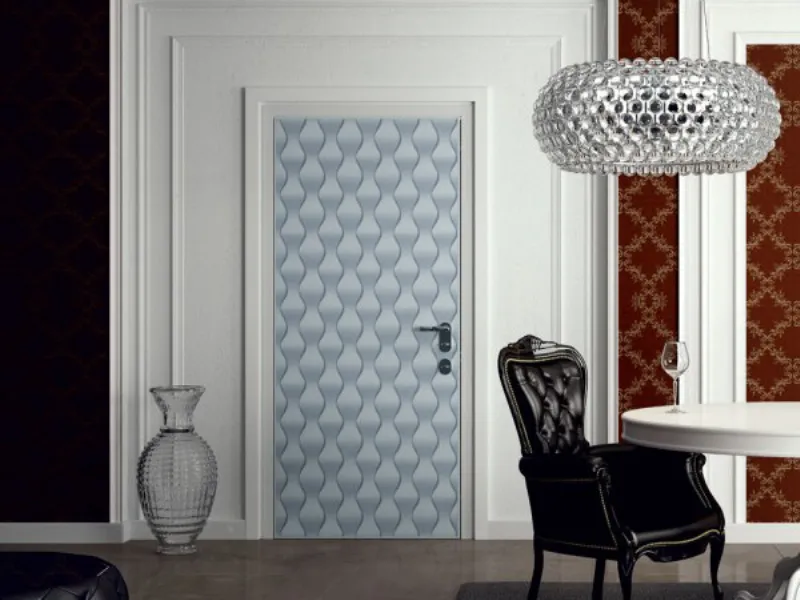 porta con fantasia azzurra geometrica a onde, vaso e lampadario in vetro trasparente, poltrona stile impero nera