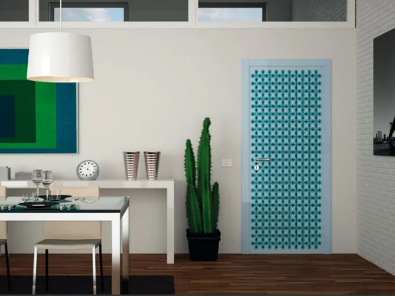 porta da interno con fantasia optical azzurra e verde, cornice azzurra, cactus, tavolo da pranzo, sgabelli e lampadario con paralume bianco