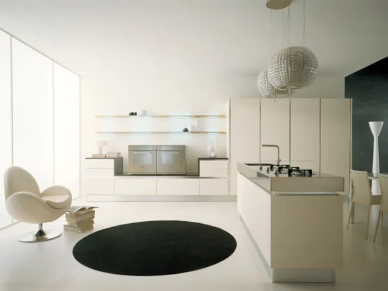 cucina living con isola nella tinta panna, poltrona design a uovo sulla sinistra in coordinato, due lampadari sferici di strass e tappeto centrale nero a cerchio
