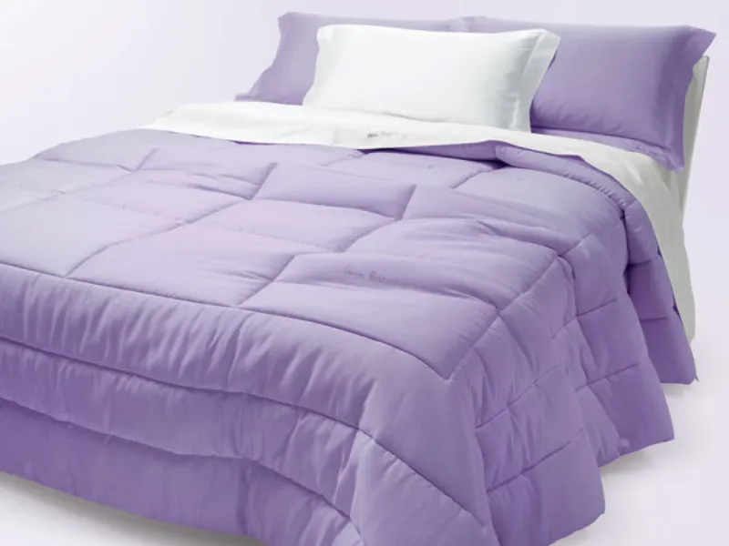 letto matrimoniale con biancheria bianca e due cuscini e copriletto lavanda