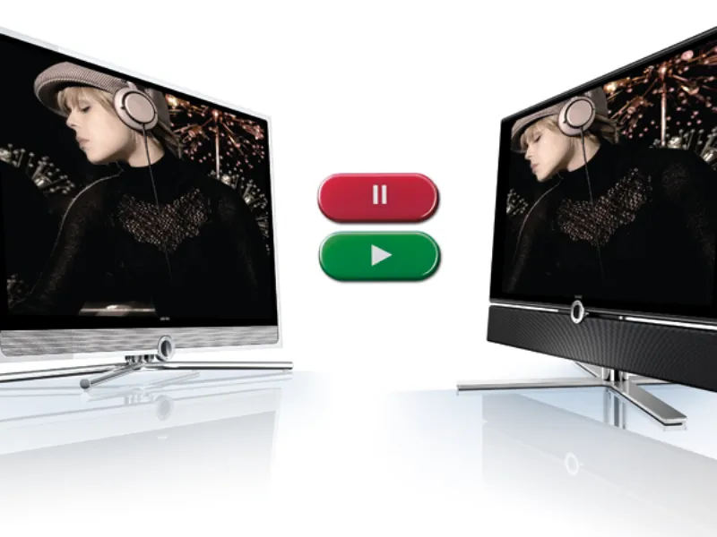 due schermi piatti Loewe con supporti a treppiede, grafica dei pulsanti Pause in rosso e Play in verde