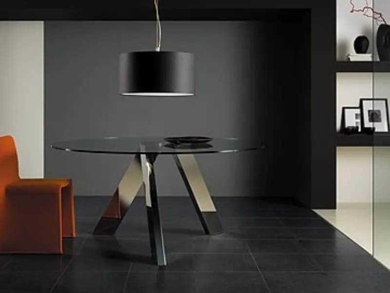 zona living con tavolino con piano in vetro trasparente circolare, seduta arancione e lampada con paralume circolare nero