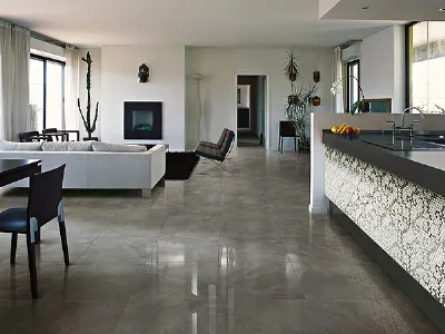 cucina e zona living con penisola con piano nero e parete rivestita a mosaico, pavimento a piastrelle di marmo, divano bianco e camino