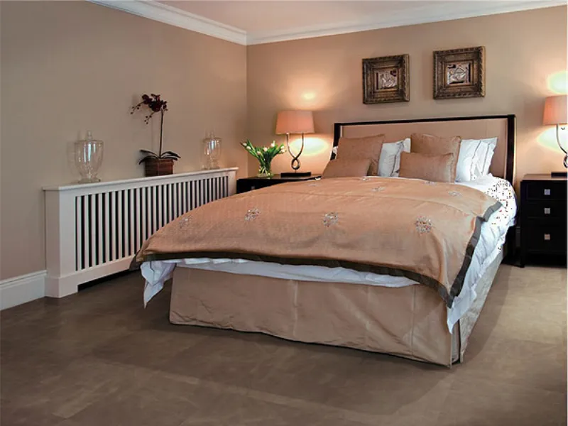 letto matrimoniale con biancheria nei toni del bianco e pesca, termo bianco lungo la parete e pavimento rivestito in pelle