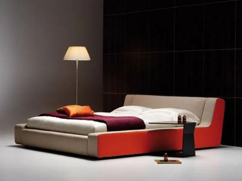 letto matrimoniale con struttura nelle tinte beige e mattone, tavolino nero e lampada da terra con paralume